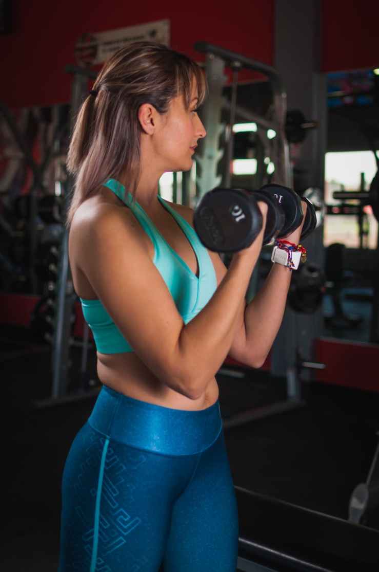 woman holding black dumbbells
